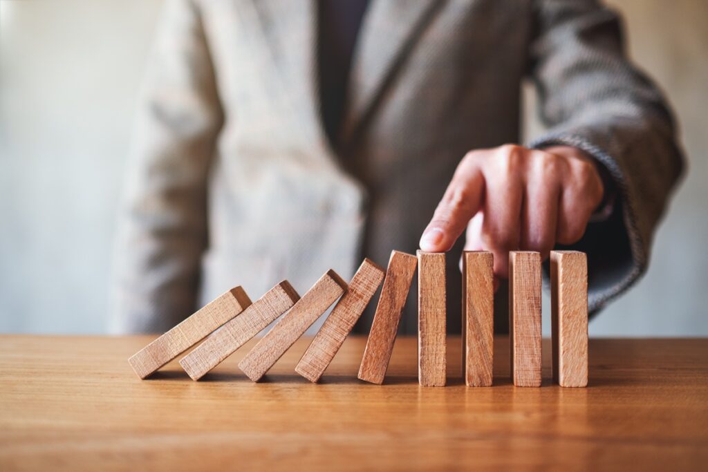 preventing-domino-effect-with-finger-on-wooden-blo-2026-01-06-00-53-15-utc.jpg